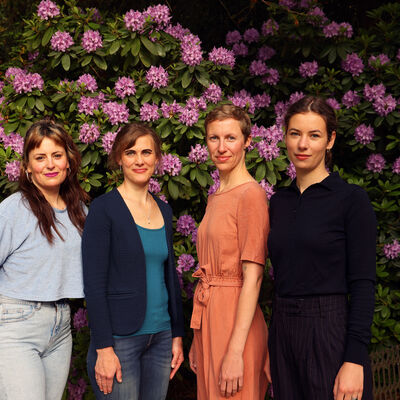 Bild vergr&ouml;&szlig;ern: Es stehen vier Personen vor einem pink bl&uuml;henden Rhododendronbusch. Von link nach rechts: Lea Pook, Andrea Enders, Marie Sprute (Gleichstellungsbeauftragte) und Friederike Rosenbaum.